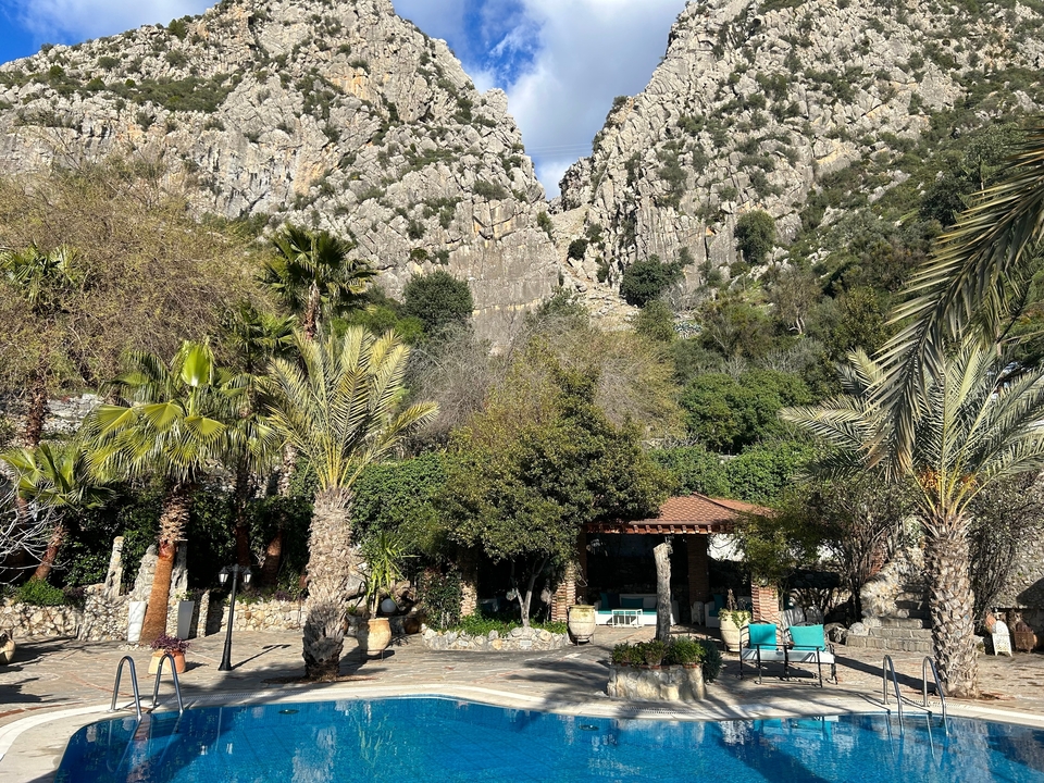 Paysage montagneux avec des palmiers et un petit bâtiment.