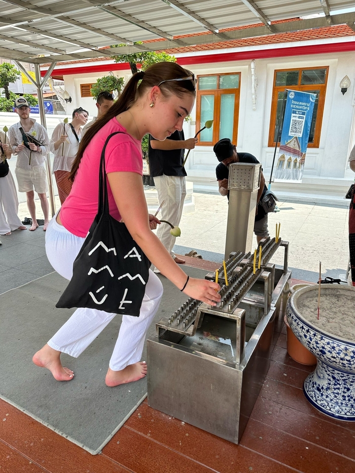 Person lighting candles at a temple offering.
