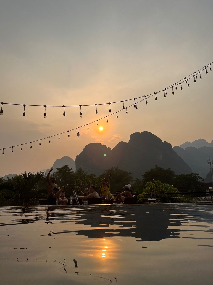 People enjoying sunset at a rooftop with mountain backdrop.