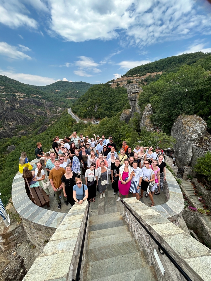 Large group of people posing in a scenic mountainous area.