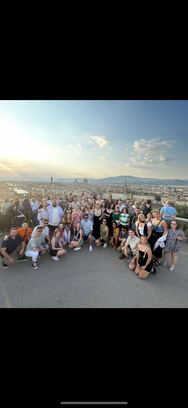 Large group of people posing with a cityscape in the background featuring Florence.