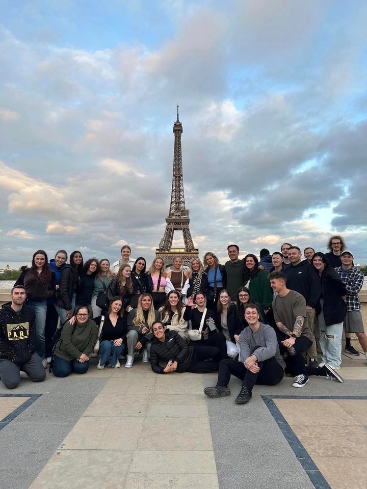 Group of people posed in front of the Eiffel Tower.