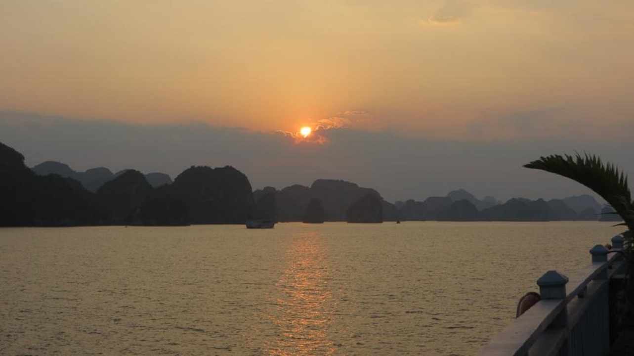 Un coucher de soleil serein sur une baie avec la silhouette d'îles.