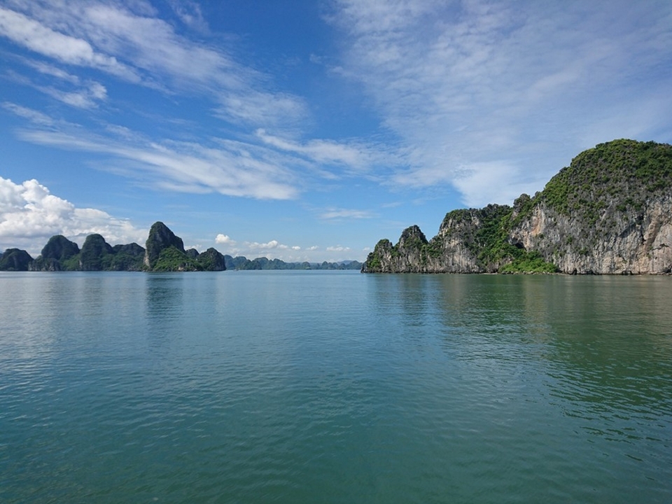 Une vue panoramique d'une baie avec des îles calcaires imposantes et un ciel bleu.