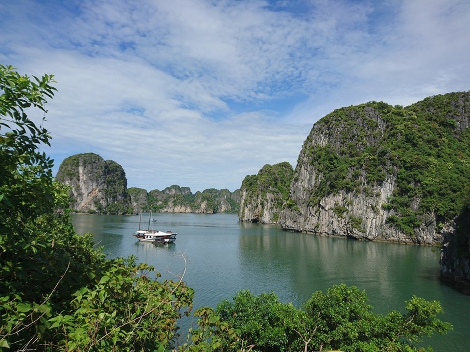 Falaises de calcaire vert entourant une baie avec un bateau visible.
