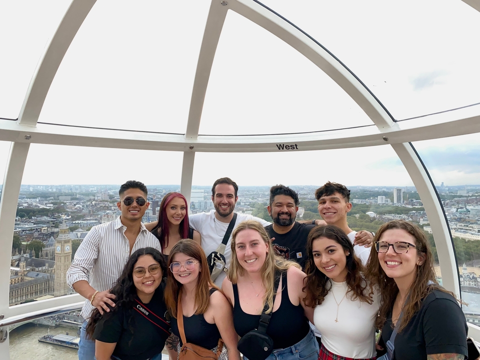 A group inside a glass capsule of a Ferris wheel with a cityscape view.