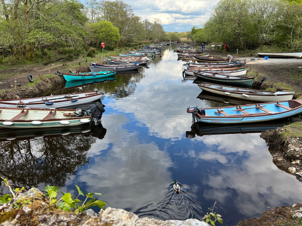 Boats floating on a narrow waterway with clear reflection.