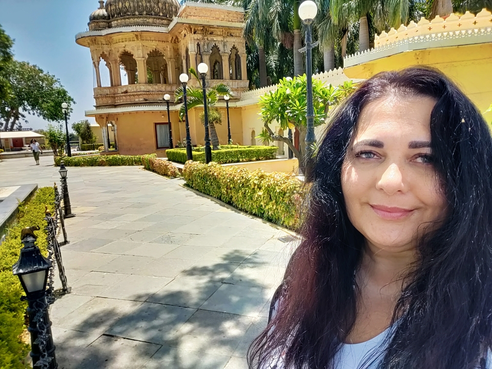 Mujer sonriendo frente a un patio histórico.