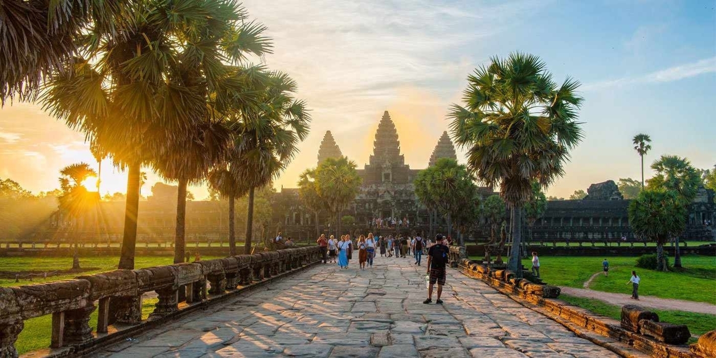People walking towards Angkor Wat at sunrise