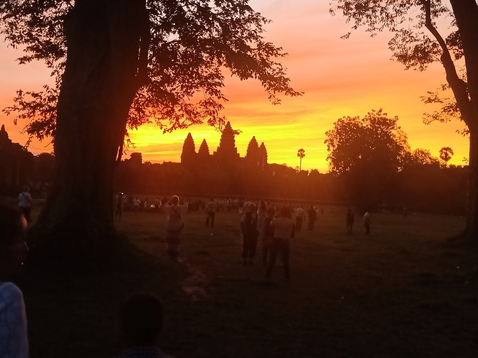 Sunset view with silhouette of a temple and people.
