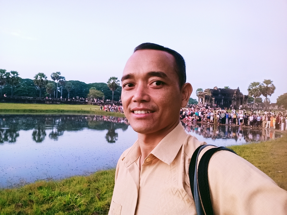 Person taking a selfie with a temple in the background.