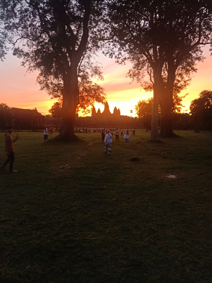 Sunset view with silhouette of a temple and people.