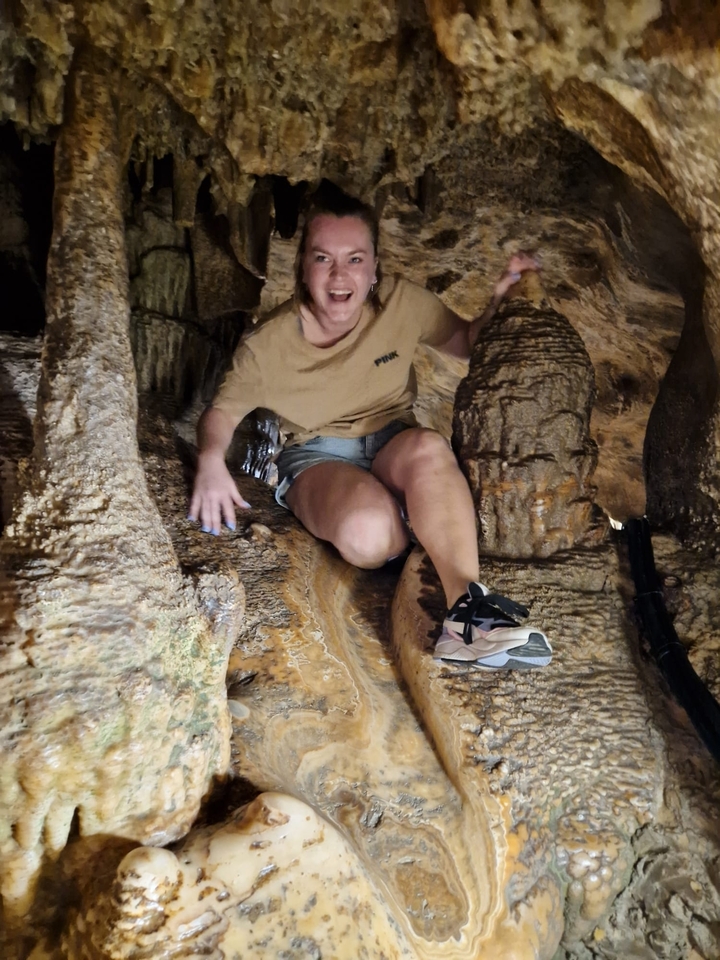 Person exploring a cave with rock formations.