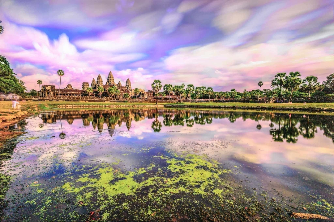Reflection of Angkor Wat in the water with a vibrant sky.