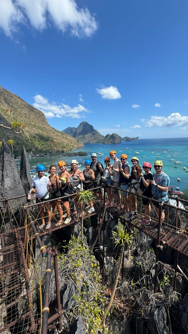 Groupe de personnes avec des casques posant sur une falaise pittoresque.