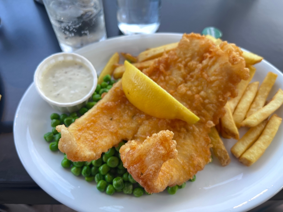 Fish and chips with peas and a lemon wedge.