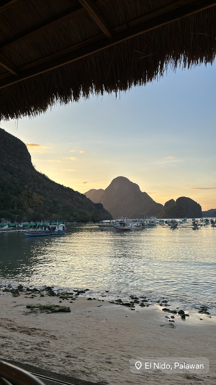 Bateaux sur une eau tranquille avec un arrière-plan montagneux au coucher du soleil.