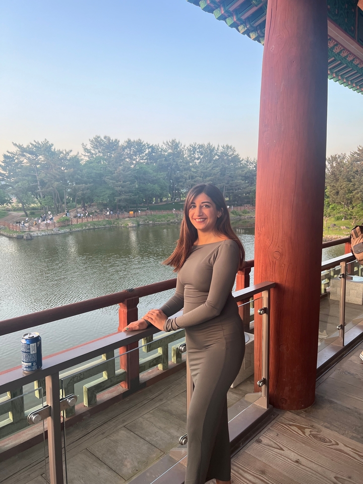 Personne qui pose près d'un lac avec des arbres en arrière-plan.