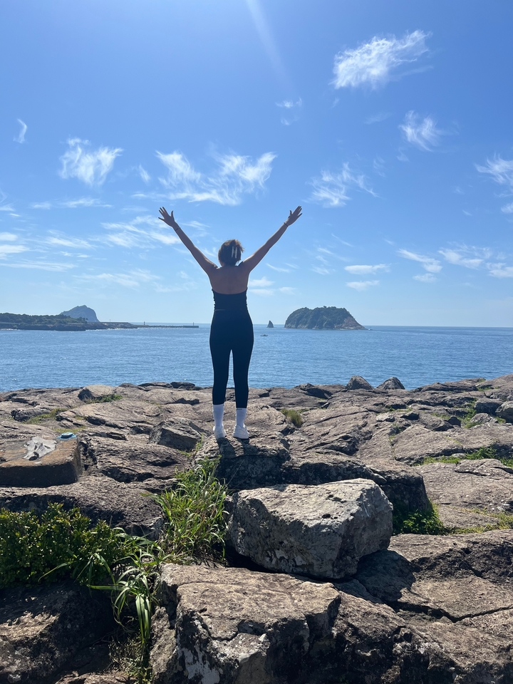 Personne les bras levés, surplombant la mer.