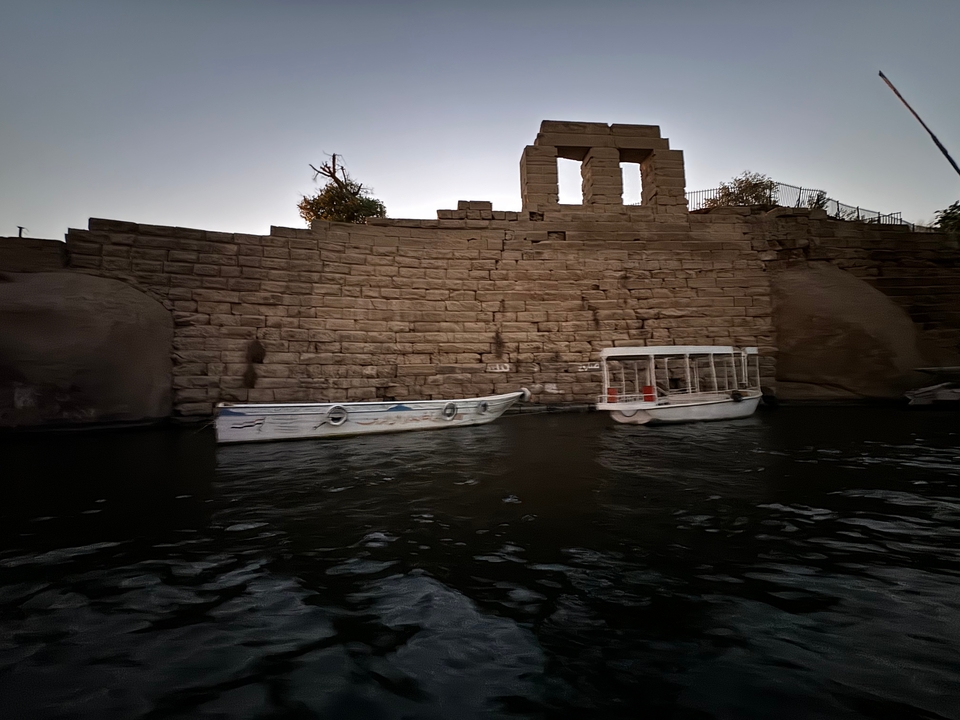 Boats moored by a stone structure on a river.