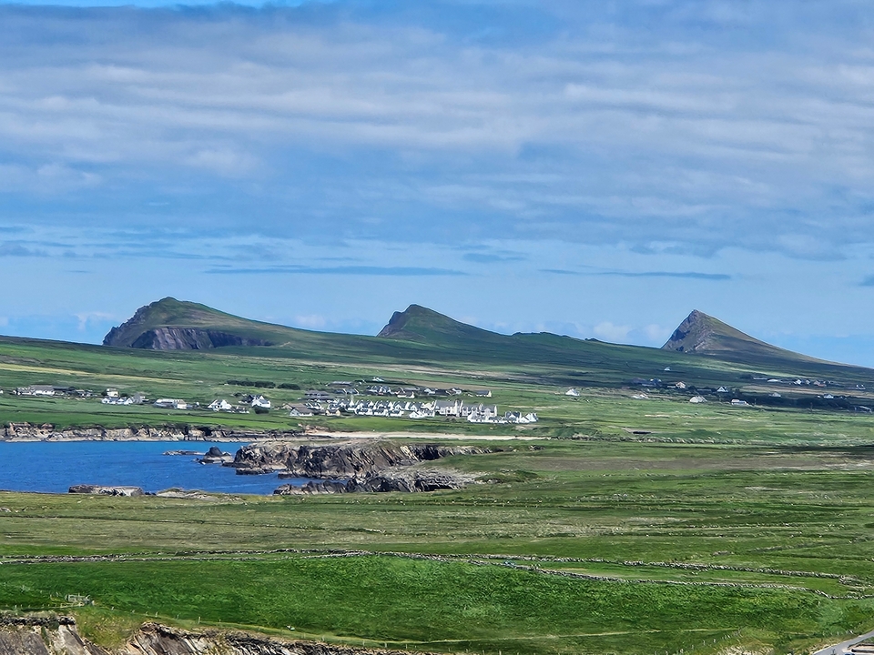 Panoramic view of a coastal village with hills in the background.