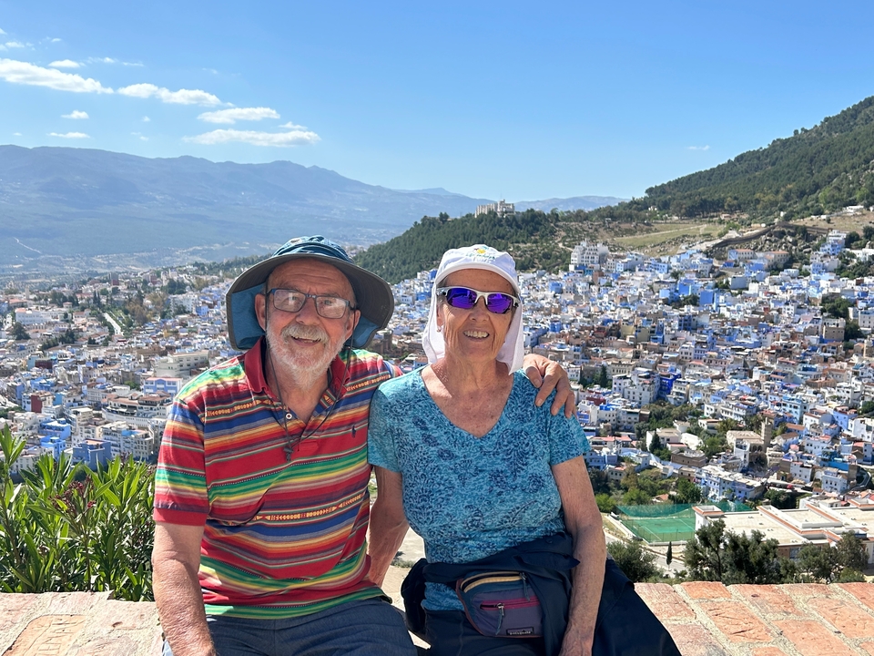 Smiling couple seated in front of a city view.
