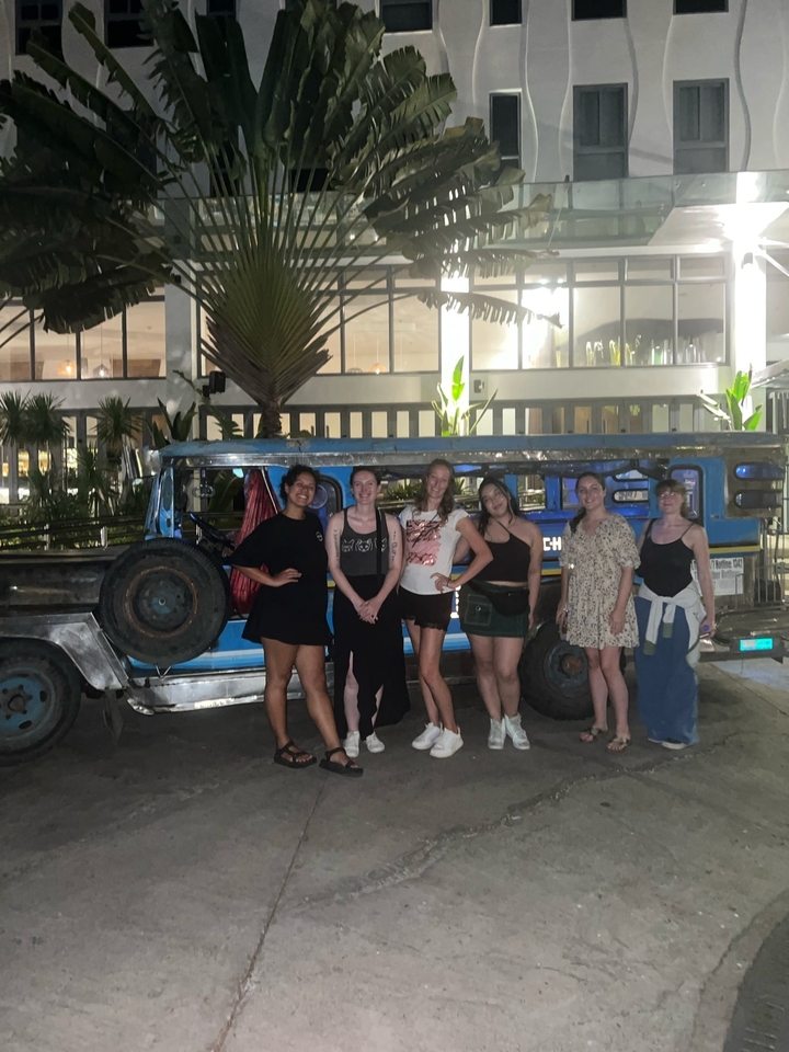 Six personnes posant devant un jeepney.