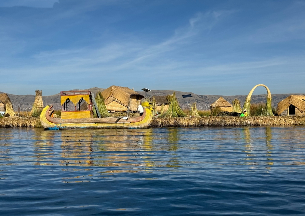 Reed islands with huts and a traditional boat on the water.