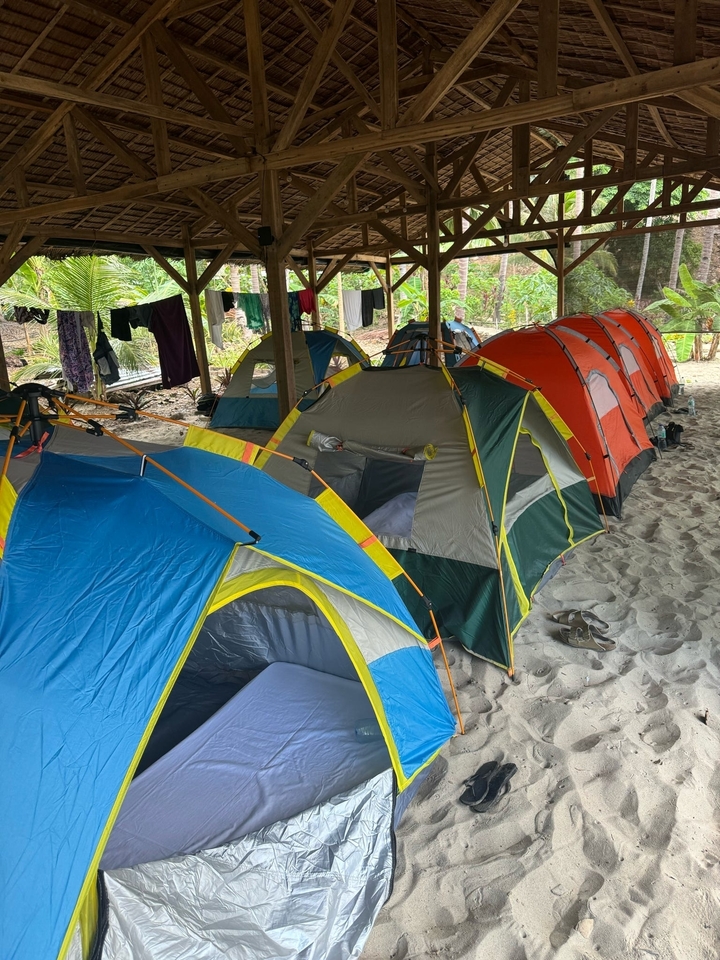 Rangée de tentes installées sur une surface sableuse.
