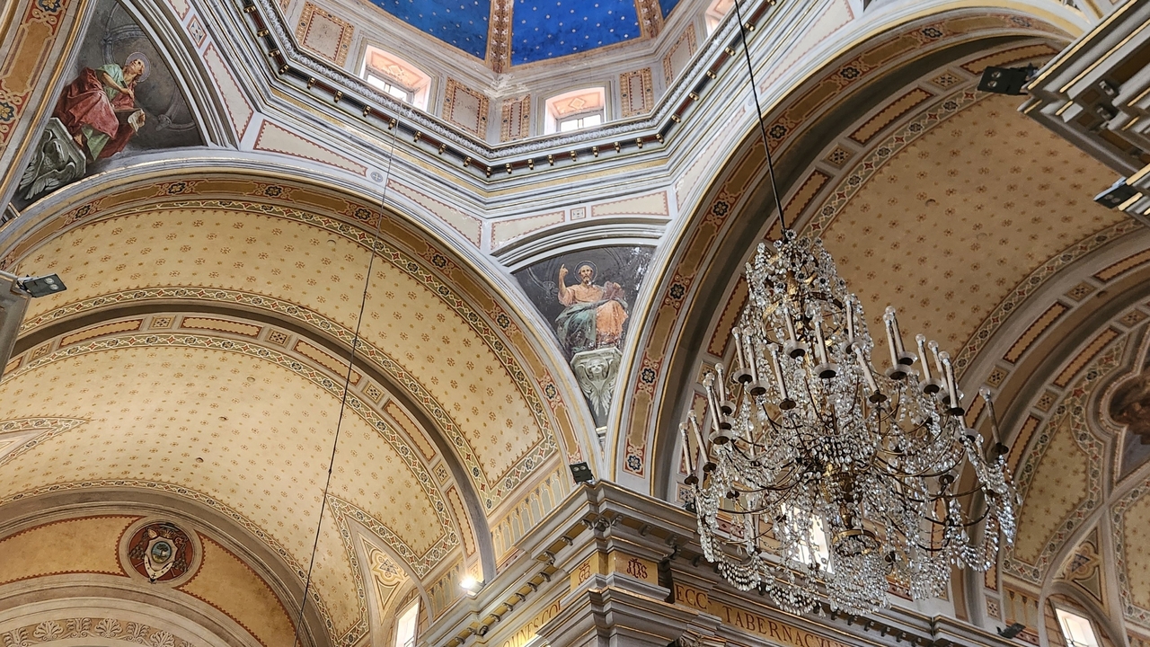 Ornate interior of a church dome with chandeliers.