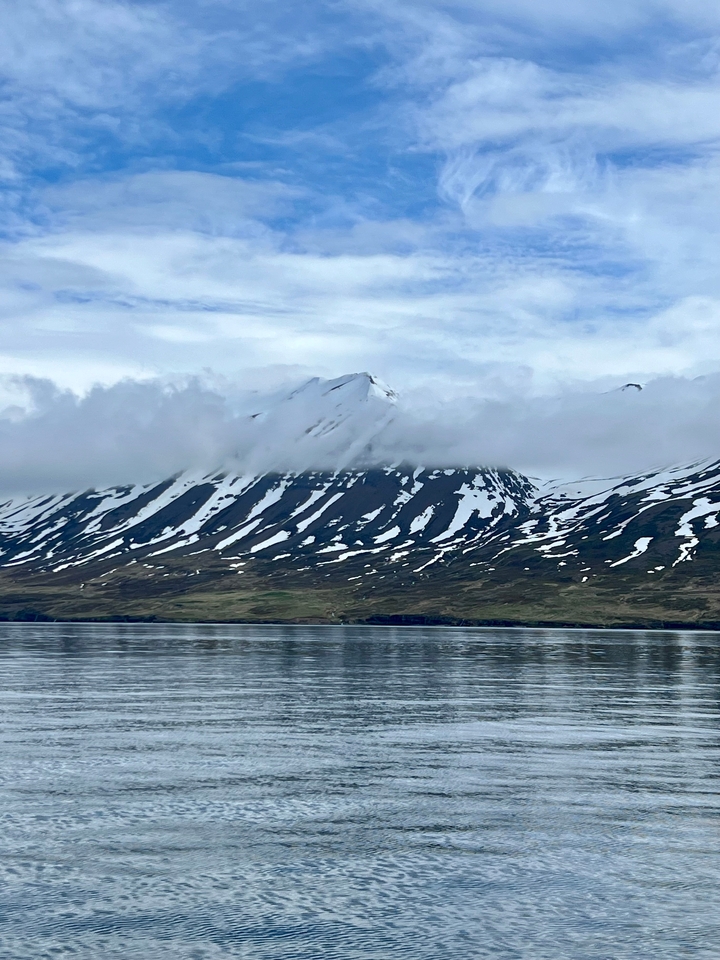 Snow-capped mountains partially covered by clouds.