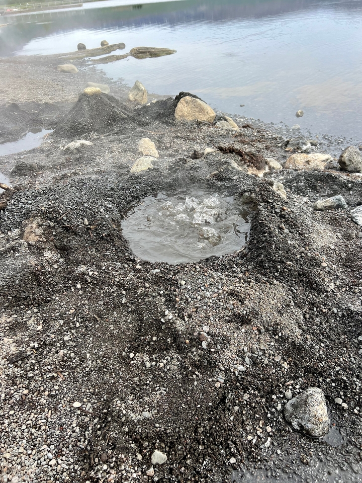 Close-up of a geothermal hot spring with bubbling water.