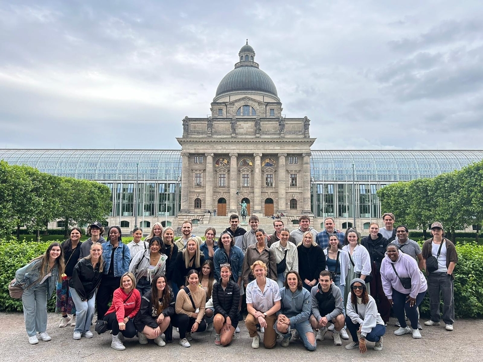 Large group in front of a historic glass house and dome building.
