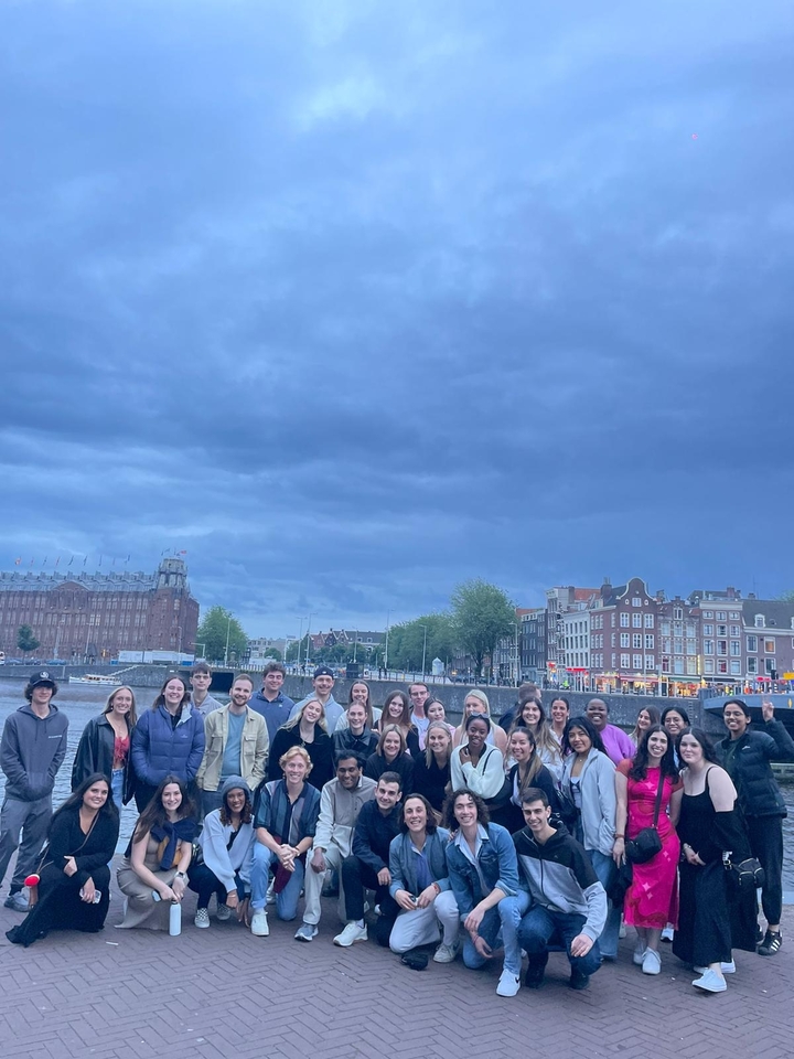 Group posing near a canal with classic architecture.
