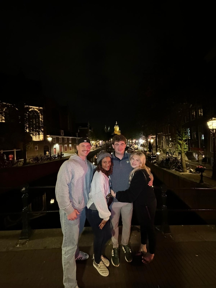 Group of friends on a nighttime cityscape bridge.