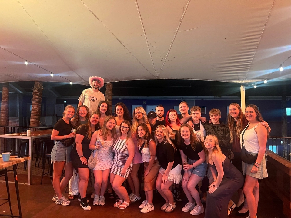 Large group of people at a social gathering under a canopy.