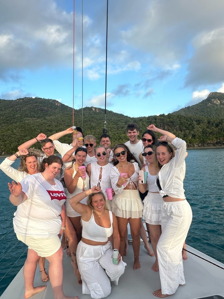 Group of people in white celebrating on a boat.