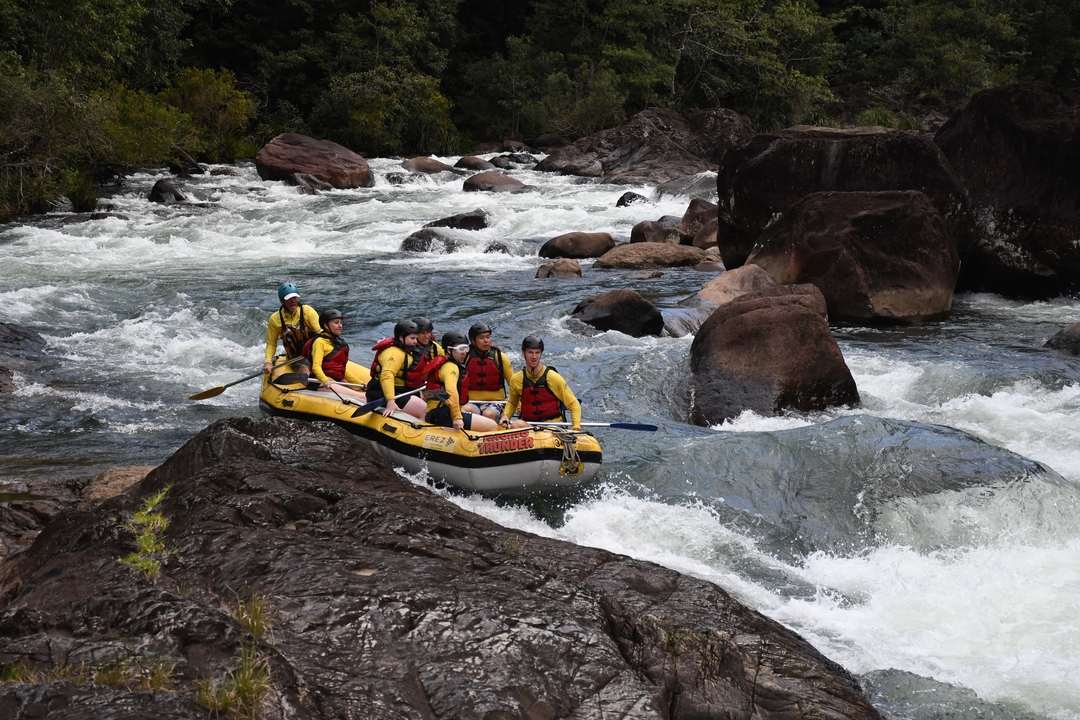 Group of people white-water rafting in a river.