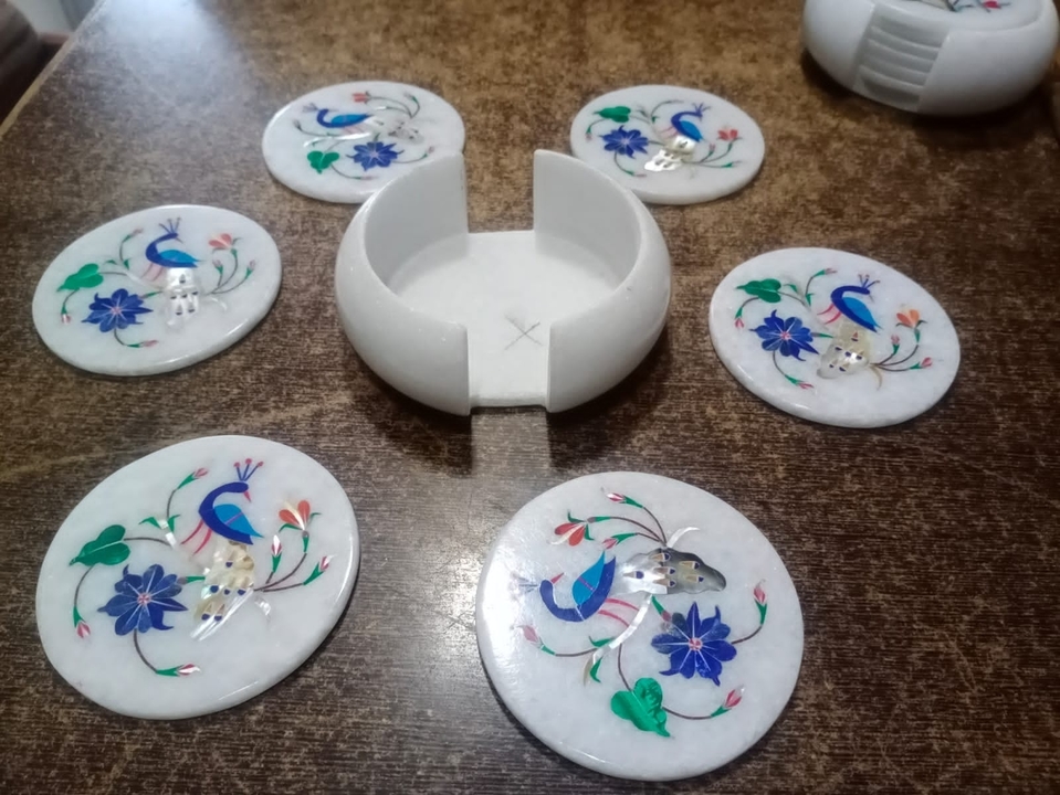 Marble coasters with decorative inlay work displayed on a table.