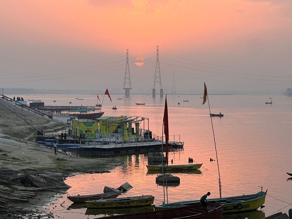 Scenic view of a river with boats and a sunset in the background.