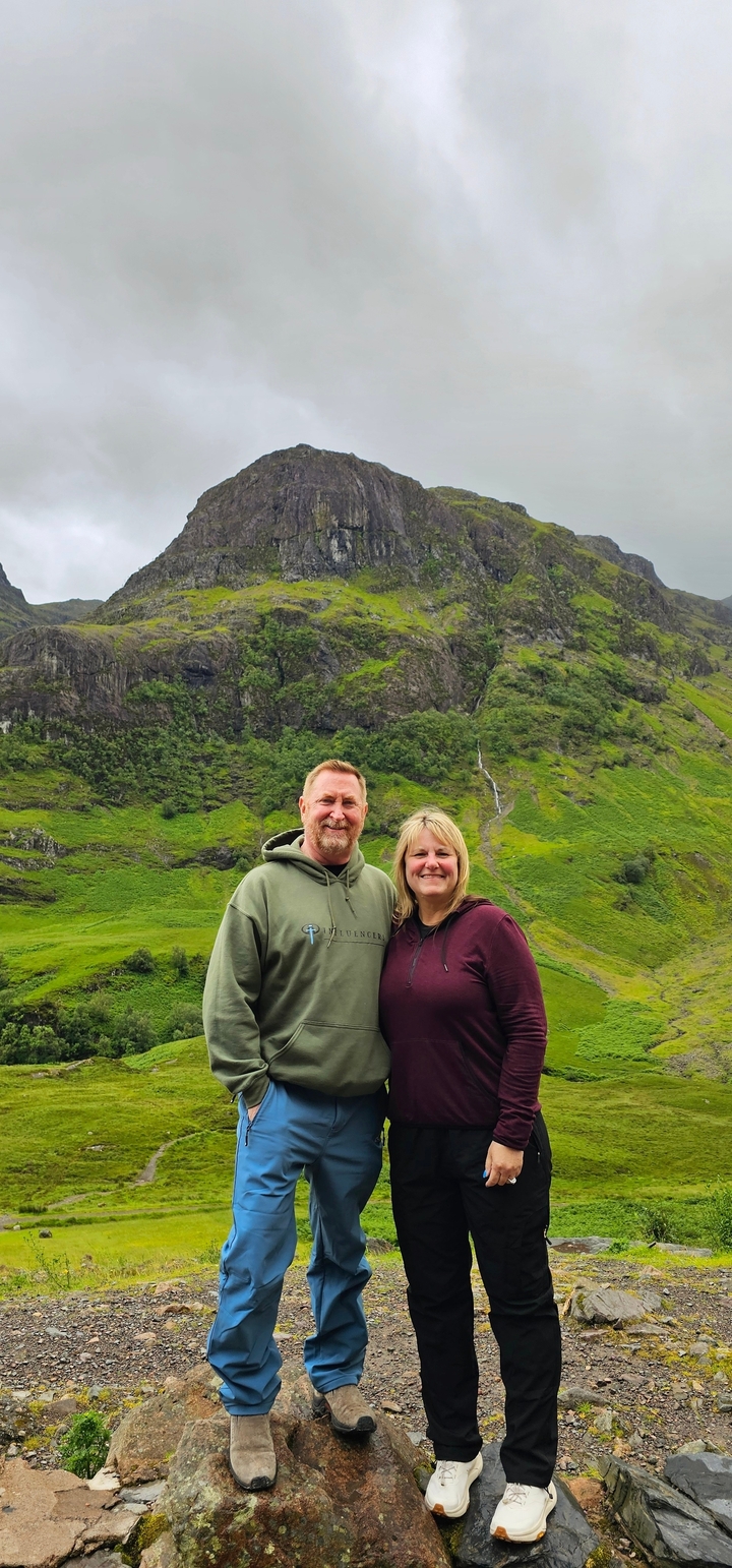 Couple posing in front of a green hillside.