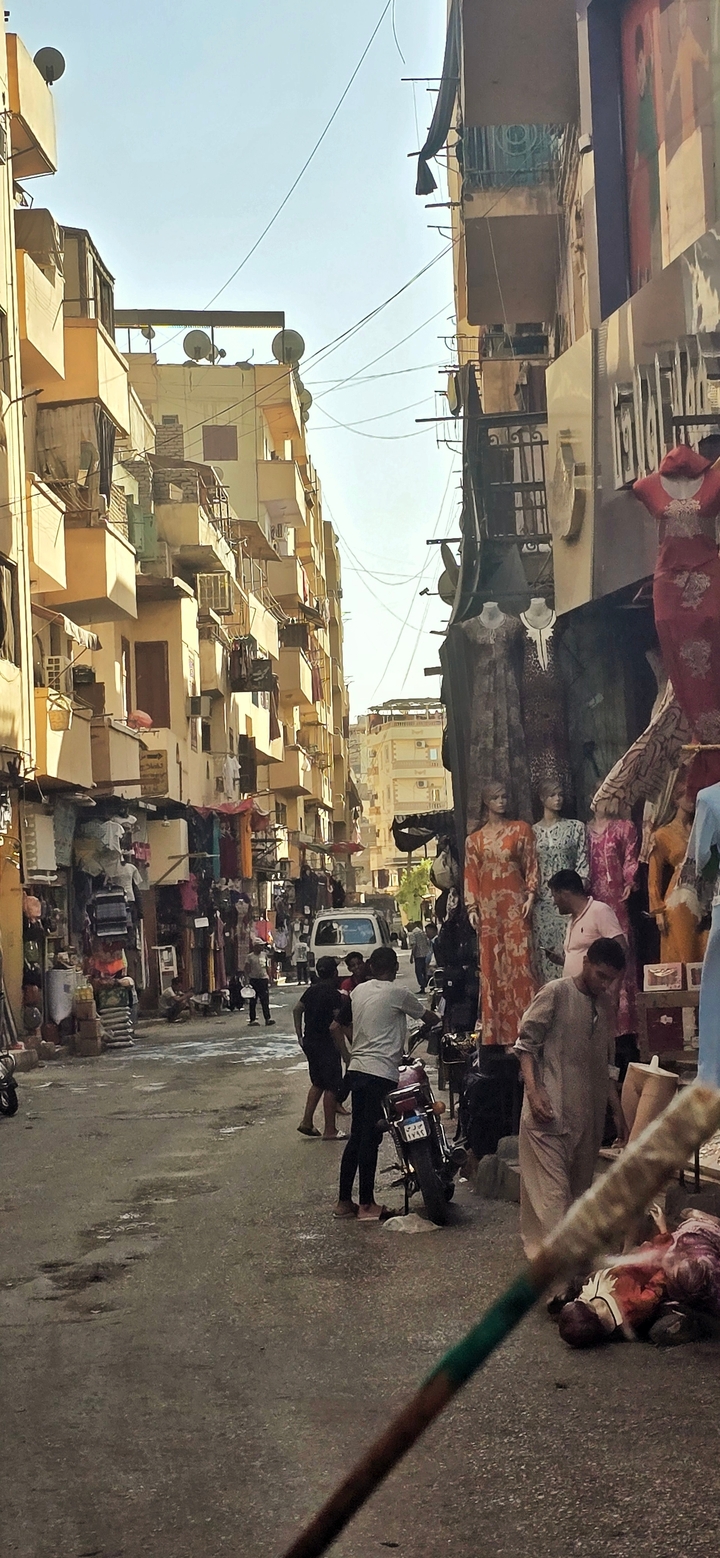 Rue de marché animée avec des vêtements et des gens.