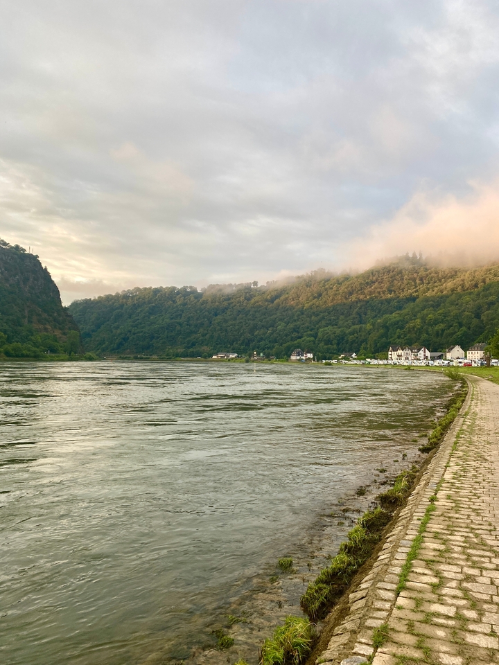 Peaceful river with hills and houses on the bank.