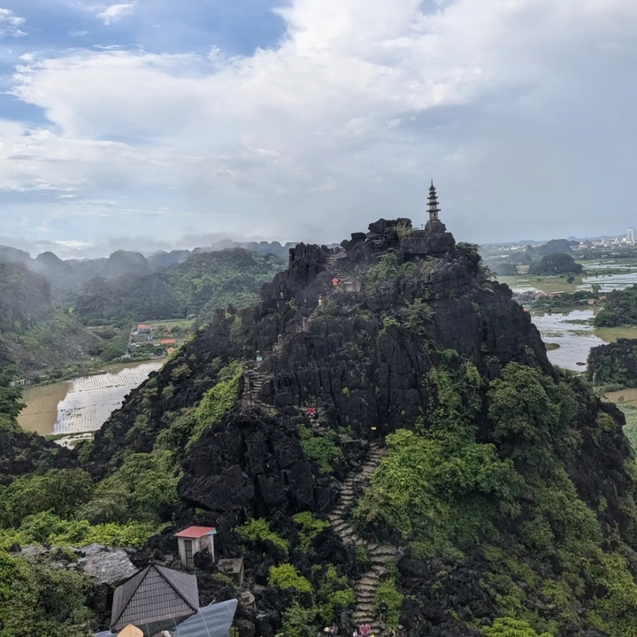 A pagoda on top of a hill with stairs carved into the rock.