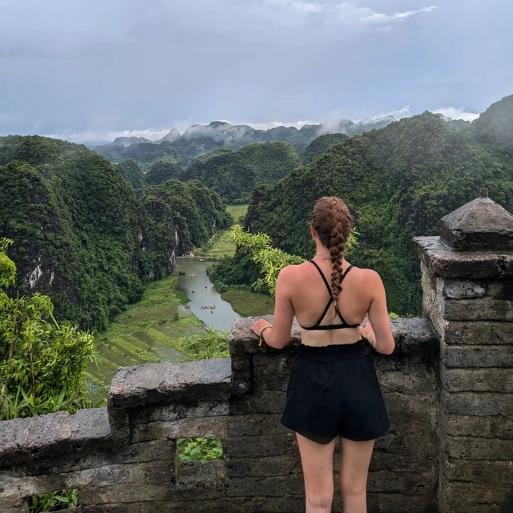 Person enjoying the view of a river valley from a stone balcony.