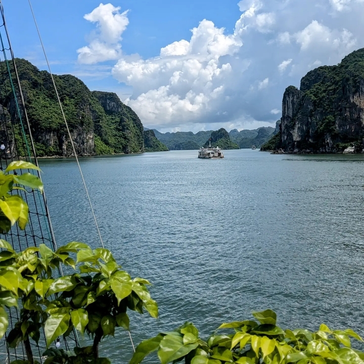 A boat sailing through Halong Bay surrounded by limestone cliffs.