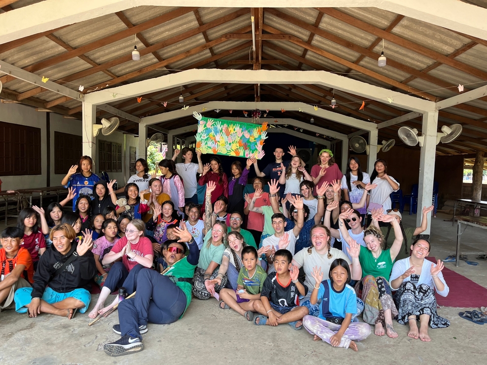 Large group of people posing joyfully inside a shelter.