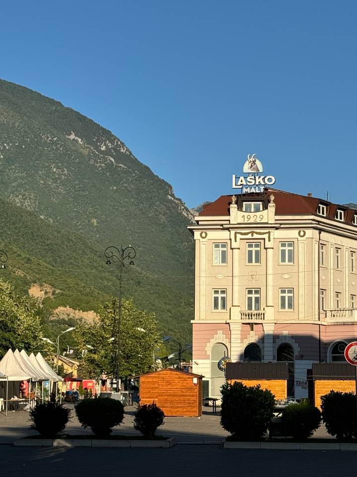 Bâtiment avec toile de fond montagneuse et enseigne Laško Malt.