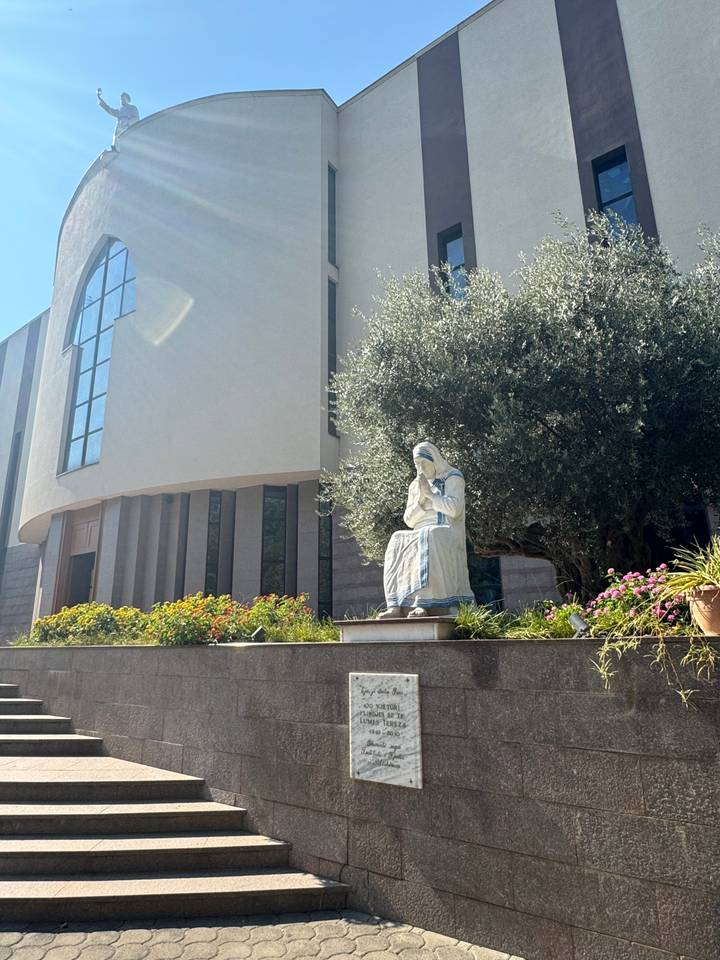 Statue d'une femme assise devant un bâtiment moderne.