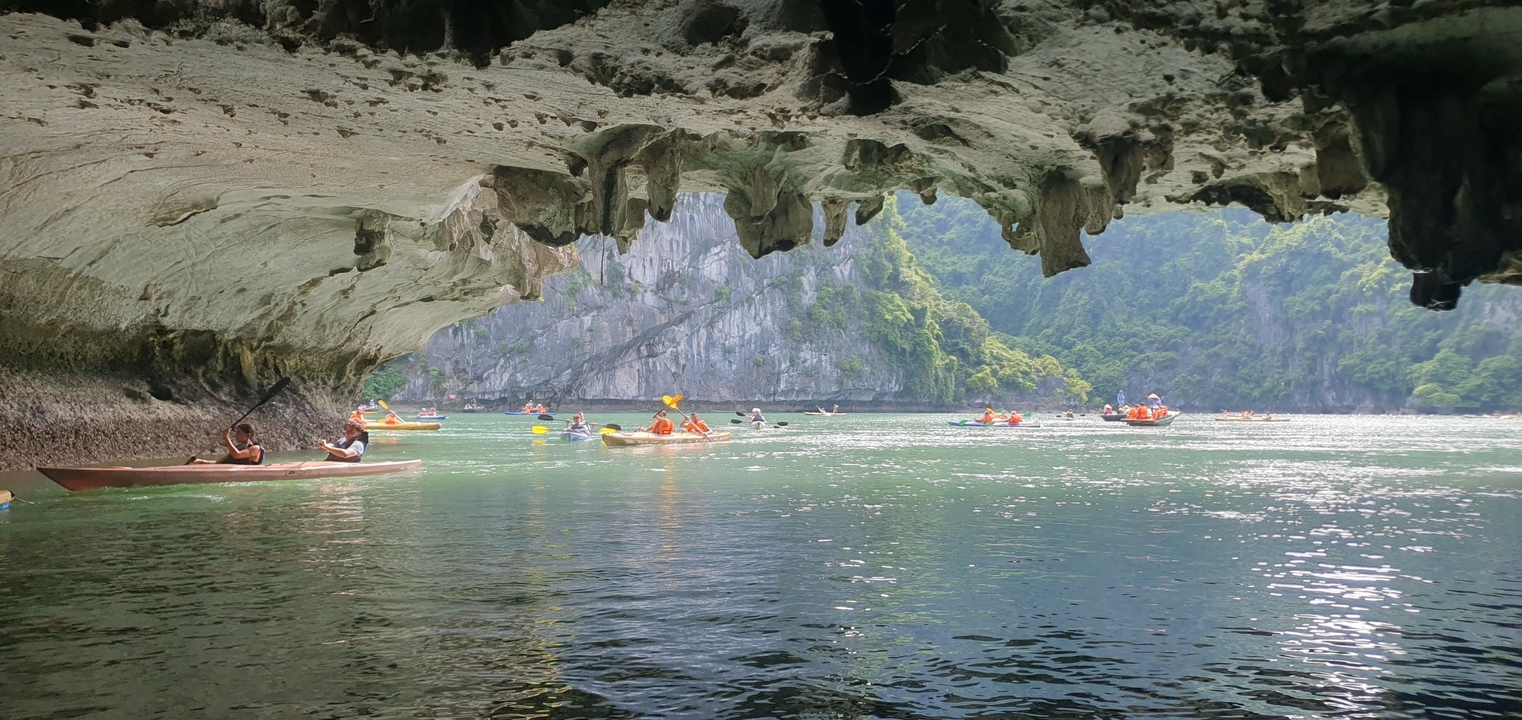 Des gens faisant du kayak dans une grotte qui s'ouvre sur des eaux pittoresques.